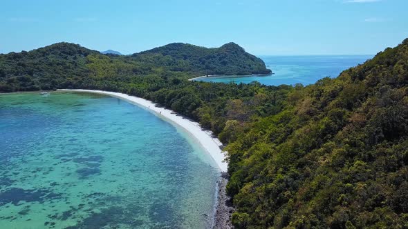 White Sand Beach With Clear Blue Lagoon And Lush Green Trees In Summer