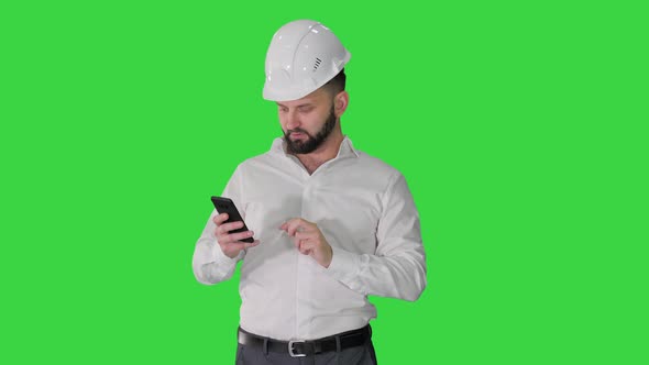 Engineer Walking and Using Smartphone on a Green Screen, Chroma Key. alt