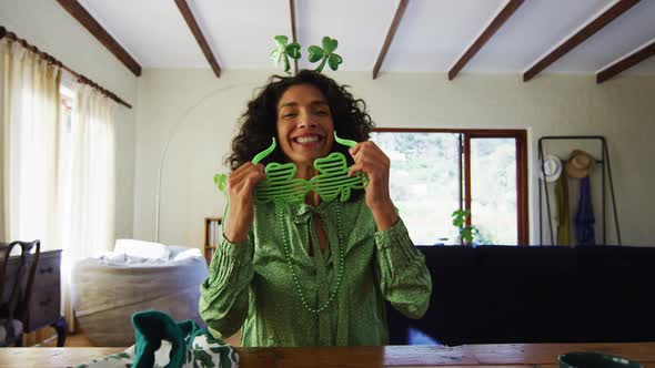 Portrait of mixed race woman wearing green glasses and costume at home alt