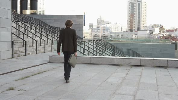 A successful businessman goes home from his favorite job going down the stairs. alt