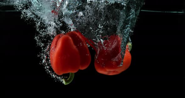 Red Sweet Pepper, capsicum annuum, Vegetable falling into Water against Black Background alt