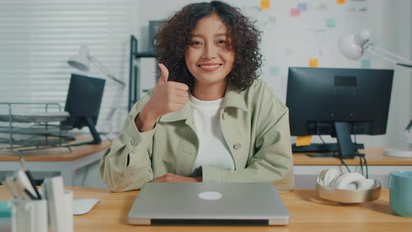 Asian Businesswoman looking at camera showing thumbs up hand sign gesture
