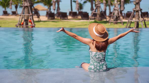 Young woman traveler relaxing and enjoying by a tropical resort pool