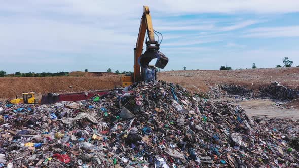 City Dump. Excavator Unloads a Truck with Garbage. Solid Waste Landfill. View From Above alt
