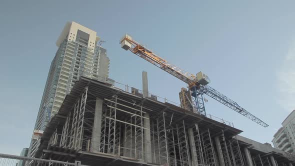 Far shot of crane on top of building in front of a tall building in downtown Toronto Canada. alt