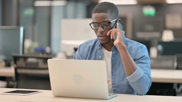 Young African American Man Talking on Phone at Work alt