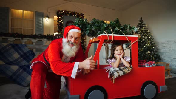 Funny Father Christmas Doing Thumbs Up Near Gladden Little Princess with Waving Hand.