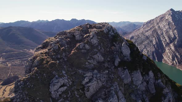 Drone above a rocky mountain summit at a really high height. Mountain top, peak covered by bushes. B alt