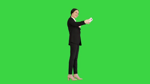Smiling Businesswoman Taking Selfie on Her Phone on a Green Screen, Chroma Key. alt