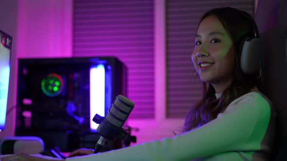 Asian gamer playing online video game winning excited on PC with lighting effect alt