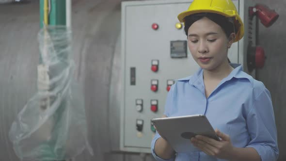 Asian female engineer or factory worker using laptop checking on an electric system alt