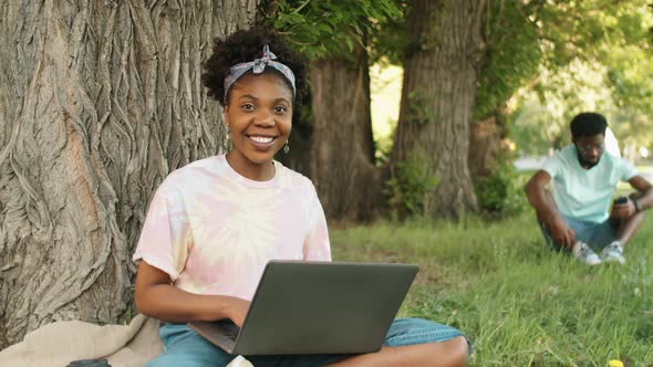 Portrait of Happy Afro-American Woman with Laptop in Park alt