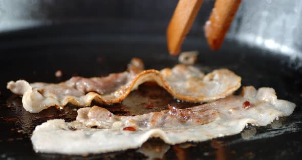 Pieces of Bacon for English Breakfast Fried with Hot Steam. On Black Background. alt