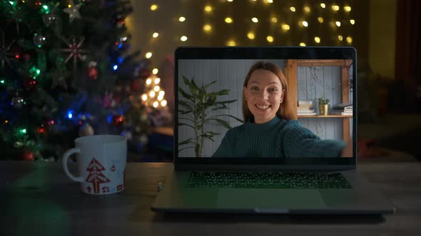 A Young Woman Waves Hello and Smiles on a Videocall