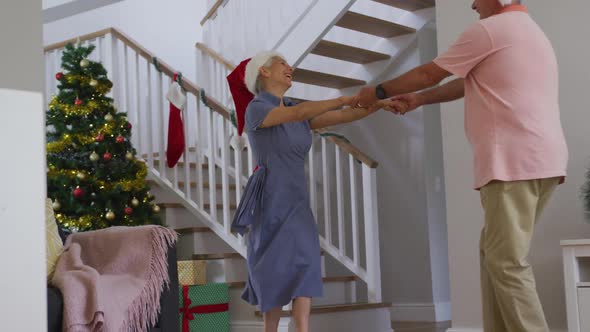 Animation of happy caucasian senior couple wearing santa hats and dancing at christmas time alt
