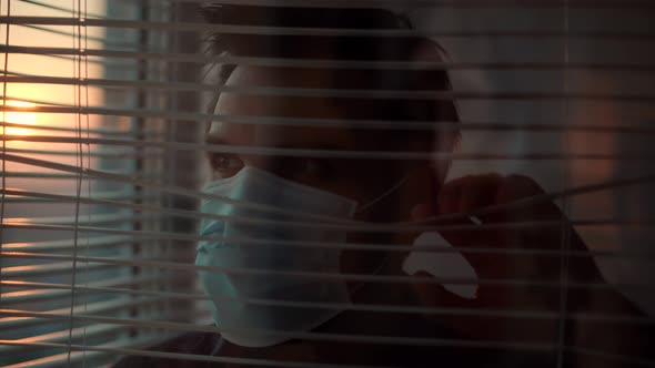 Sad Man In Face Mask Looking Through Window. Lockdown Stay At Home. Stay Home Self Isolation. alt
