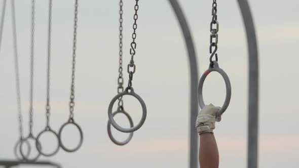 Individuals swinging on traveling rings on Santa Monica beach. alt