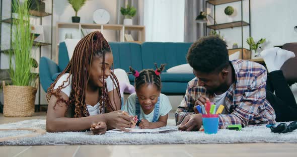 African Couple Drawing with Daughter on Floor alt