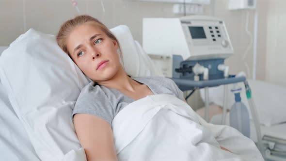 A Sick Young Woman Lying in a Hospital Bed and Waiting a Doctor alt
