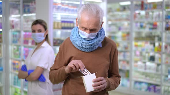 Portrait of Happy Senior Man Advertising Pills Standing in Covid19 Face Mask in Pharmacy with alt