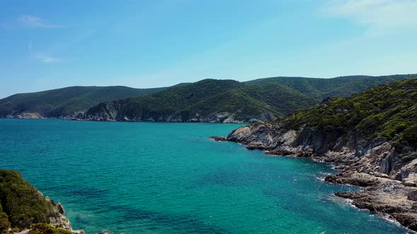 Aerial view of turquoise blue crystal clear water and rocky coast line with island view discovering alt