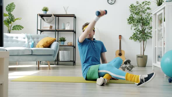 Slow Motion of Young Man Exercising with Dumbbells Then Relaxing Sitting on Fitness Mat Alone at alt