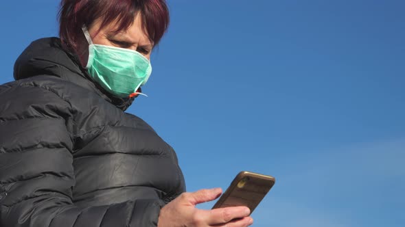 A View of the Lady Looking at Her Phone with the Face Mask on in Finland