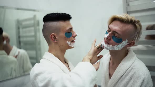Male Couple Having Fun Applying Shaving Foam Doing Morning Routine Together in Bathroom alt