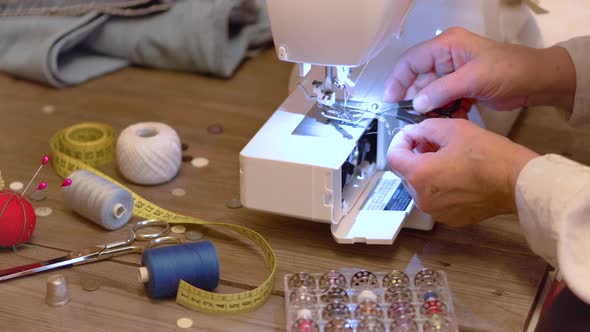 Senior Seamstress Hands Preparing the Thread of the Electrical Sewing Machine alt