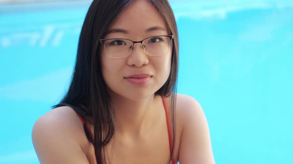 Closeup View of Asian Ethnicity Placed Lady in Glasses Sitting in Poolside at Home Hotel Spa alt