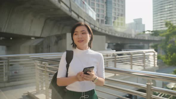 Portrait of asian woman with earphone listening music and using smartphone