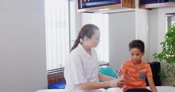 Female physiotherapist giving hand massage to boy patient 4k alt