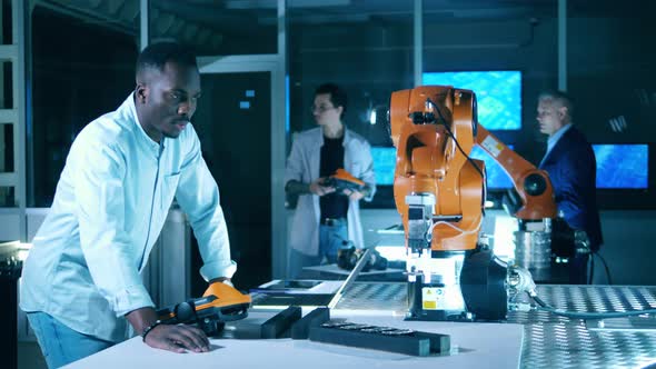 African Ethnicity Researcher Is Operating a Robot with an Electronic Device alt