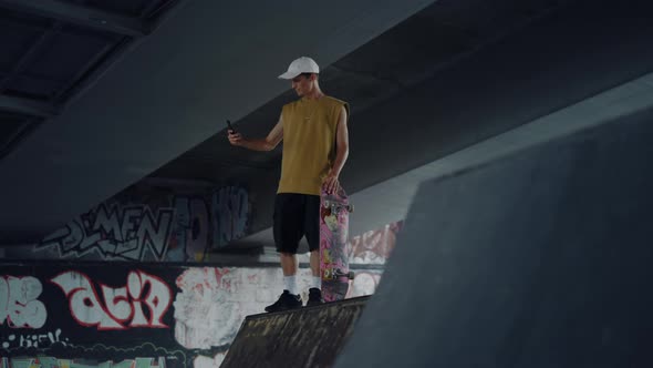 Attractive Man Using Cellphone for Self Portrait at Skate Park with Graffiti alt