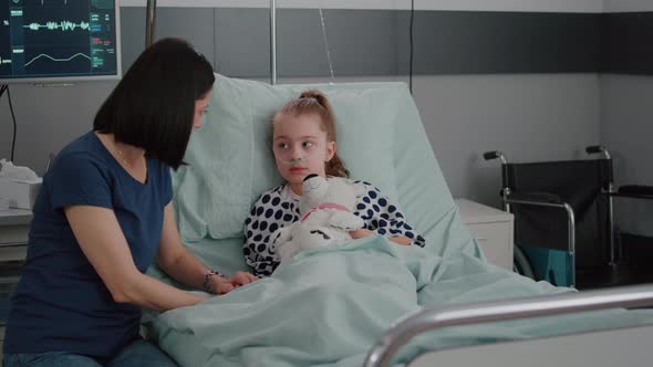 Mother Explaining Medication Treatment to Sick Daughter During Recovery Examination alt