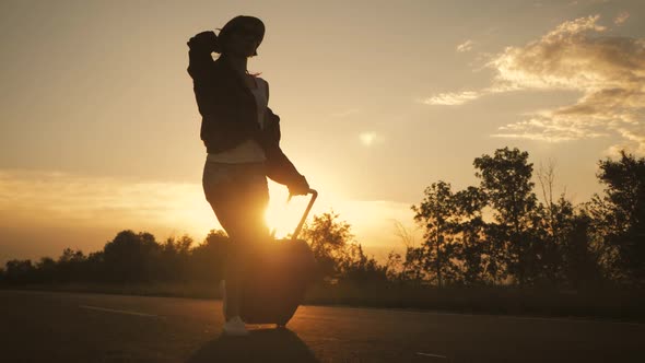 Young Woman with a Suitcase on Road. alt