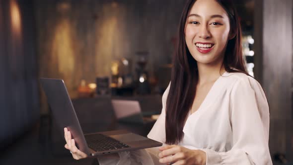 Business owner attractive young asian woman in apron hanging we're open sign. alt