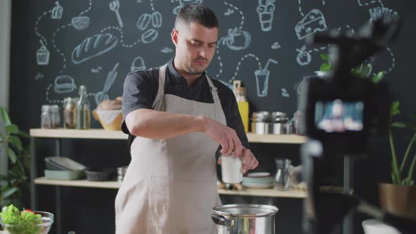 Male Vlogger Cooking and Speaking on Camera alt