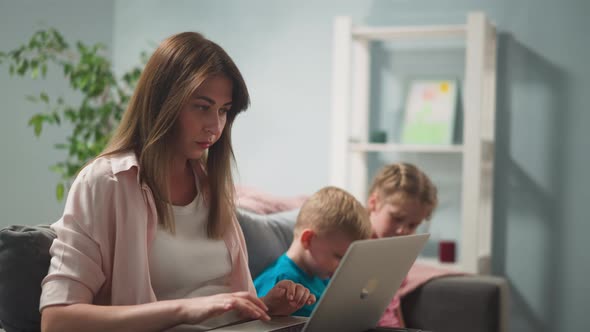 Lady Types on Laptop Quiet Children Watch Video Via Tablet alt