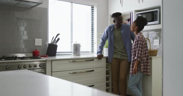 Video of happy african american couple talking in kitchen alt