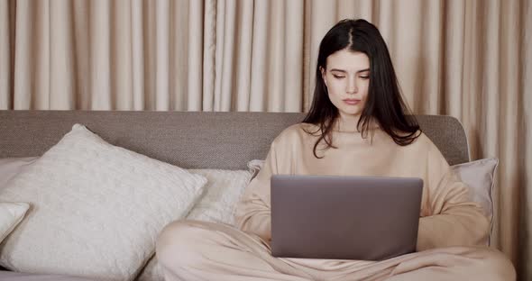 Attractive Woman Typing on Keyboard Working with Laptop Computer in Bedroom alt