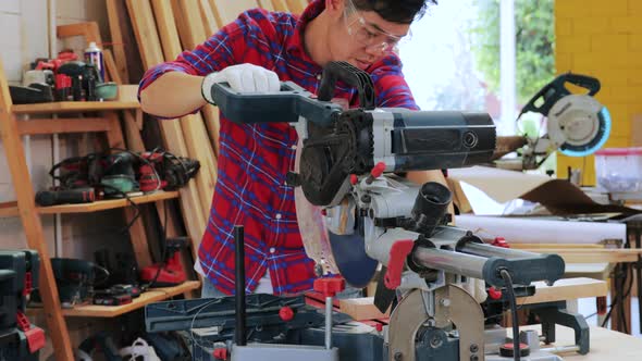 Asian carpenter cutting wood for built-in furniture project