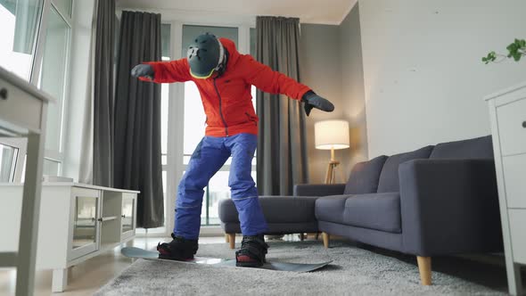Fun Video. Man Dressed As a Snowboarder Rides a Snowboard on a Carpet in a Cozy Room. Waiting for a alt