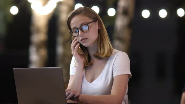 Рipster Girl in Casual Talking Via Mobile Phone and Doing Freelance Work on Netbook in a Park in alt