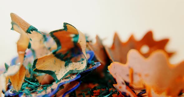 Various colored pencil shavings on wooden background alt