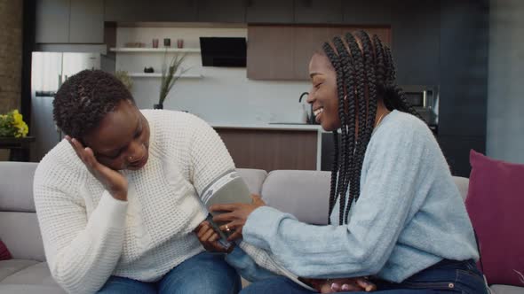 Worried Teenage Daughter Checking Blood Pressure of Unwell Mom alt