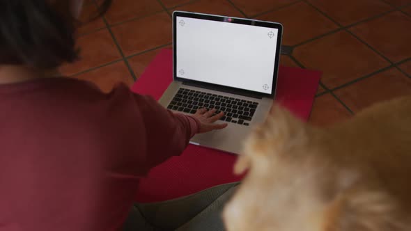Caucasian woman practicing yoga with her pet dog using laptop with blank screen at home alt