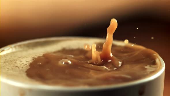 Drops Fall Into a Mug of Coffee with Milk alt