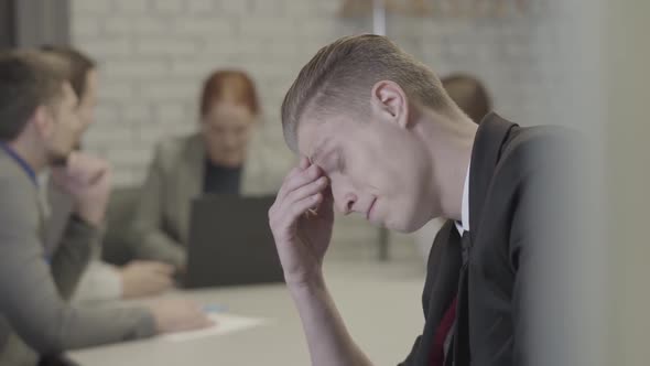Side View Portrait of Bored Caucasian Redhead Man Rubbing Eyes and Making Faces As His Colleagues alt