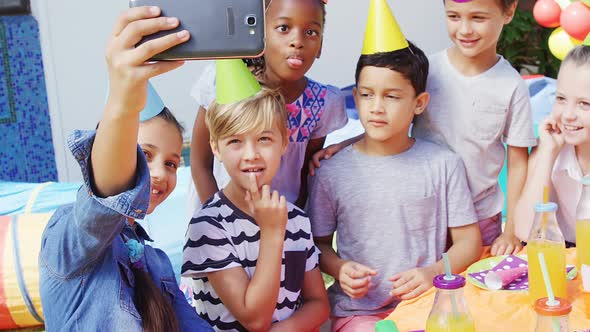 Kids taking selfies with mobile phone in the backyard of house 4k alt